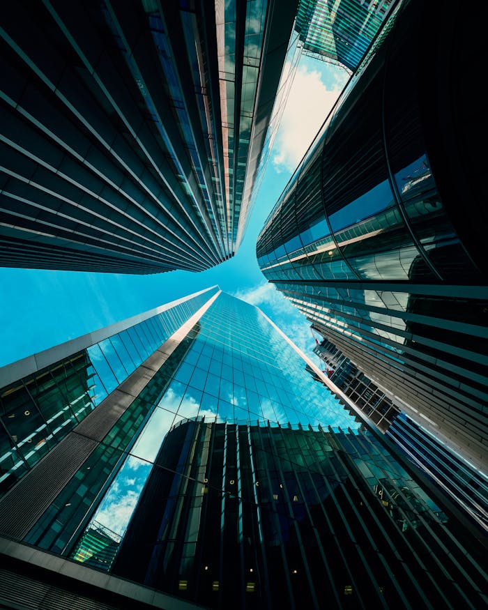 footer-cta Low-angle view of modern skyscrapers reflecting the blue sky in a bustling urban area.
