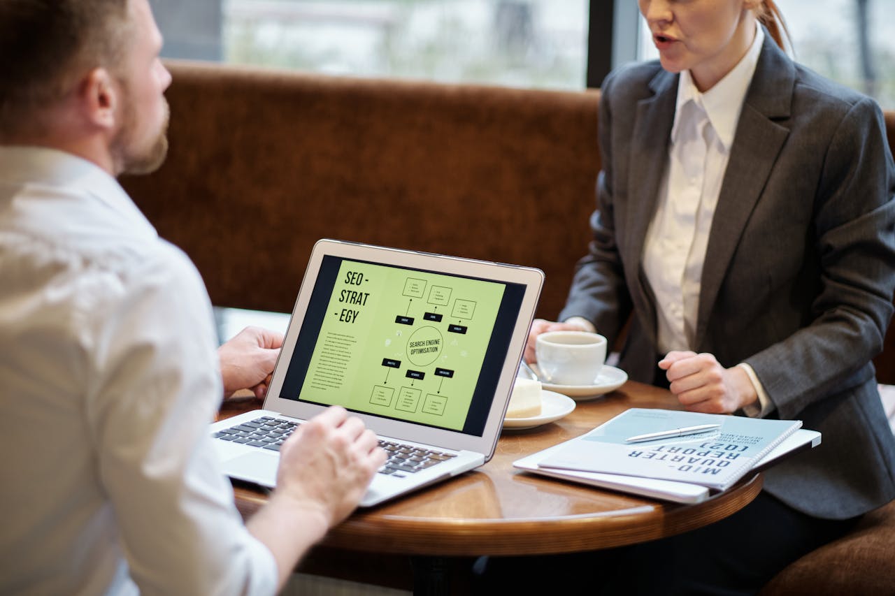 home-hero A man and woman engaged in a business meeting discussing SEO strategy in a cozy cafe setting.