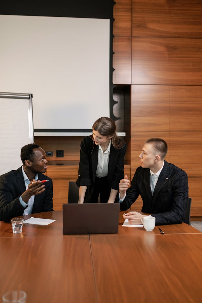 Professional team discussing around a laptop in a modern conference room.